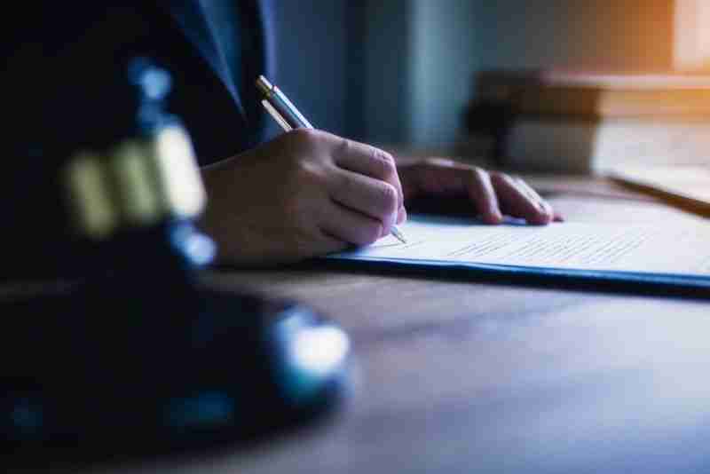 Judge signing papers on dark desk
